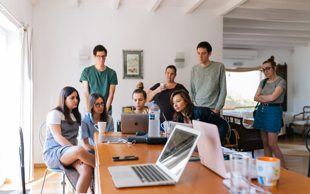 a group of young adults gathering round a laptop